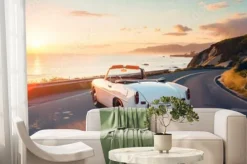 Fototapeta: Kabriolet vintage jadący nadmorską autostradą o zachodzie słońca