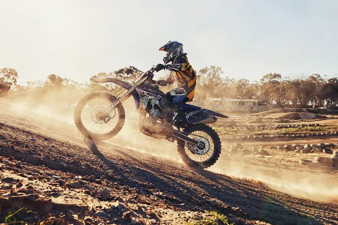 Fototapeta: Motocyklista jadący po wzgórzu