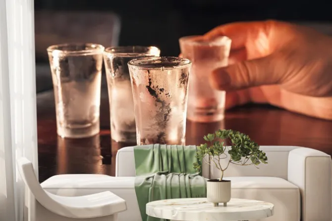 Fototapeta: Strzał kieliszek wódki w ręce na drewnianym stole.