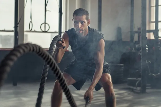 Fototapeta: Umięśniony mężczyzna ćwiczy z liną