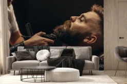 Fototapeta: Young bearded man getting beard haircut by hairdresser