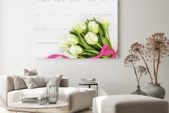 Obraz: Białe tulipany ozdobione czerwoną wstążką na białym obrusem.