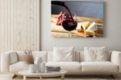 Obraz: Wylewanie czerwonego wina do szklanki na drewnianym stole