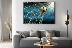 Plakat: Piłka nożna wpadająca do bramki na tle reflektorów