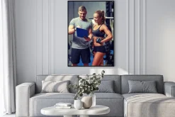 Plakat: Uśmiechnięta młoda kobieta z osobistym trenerem w siłowni